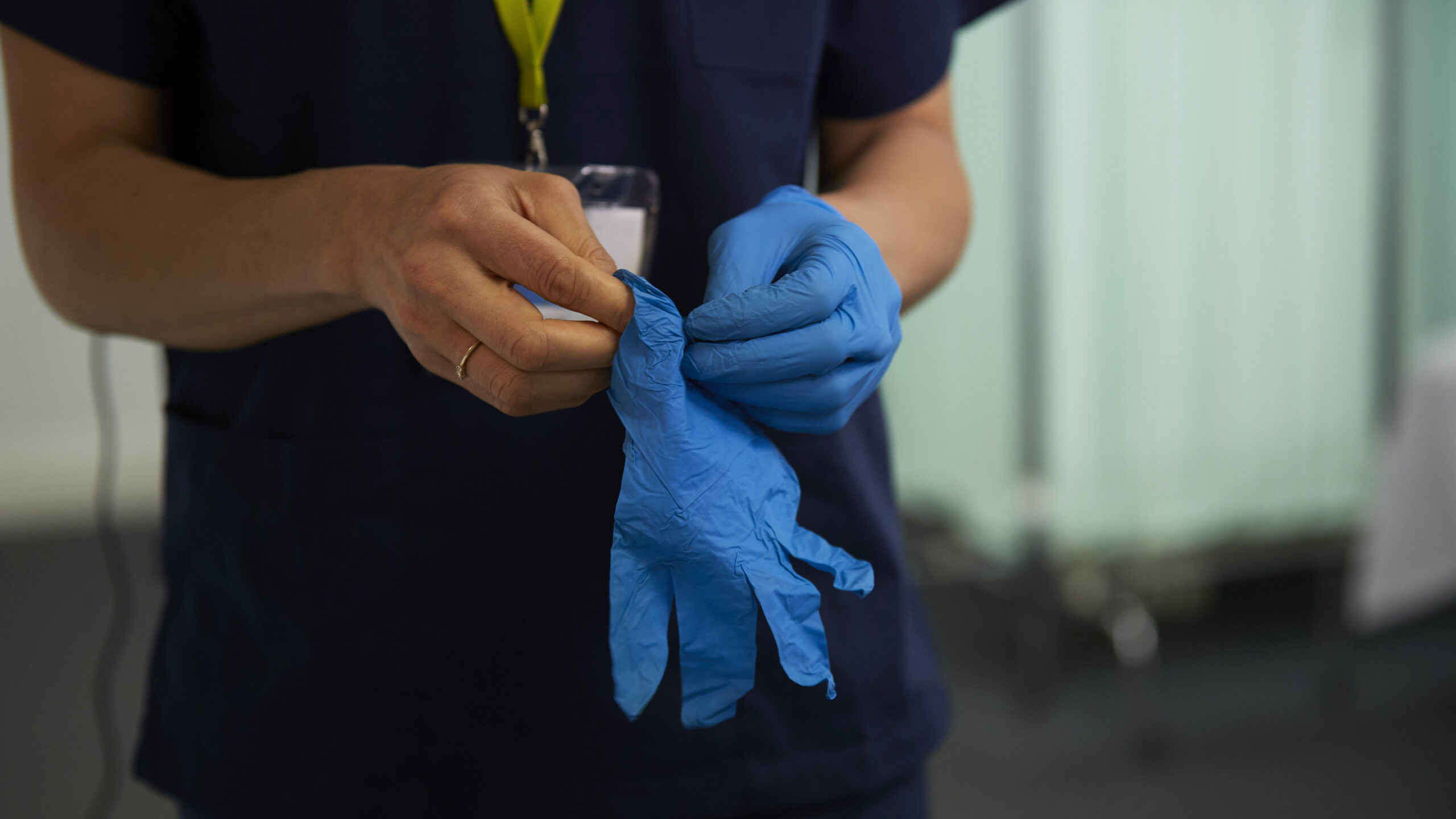 Close up of medical professional putting on medical gloves.